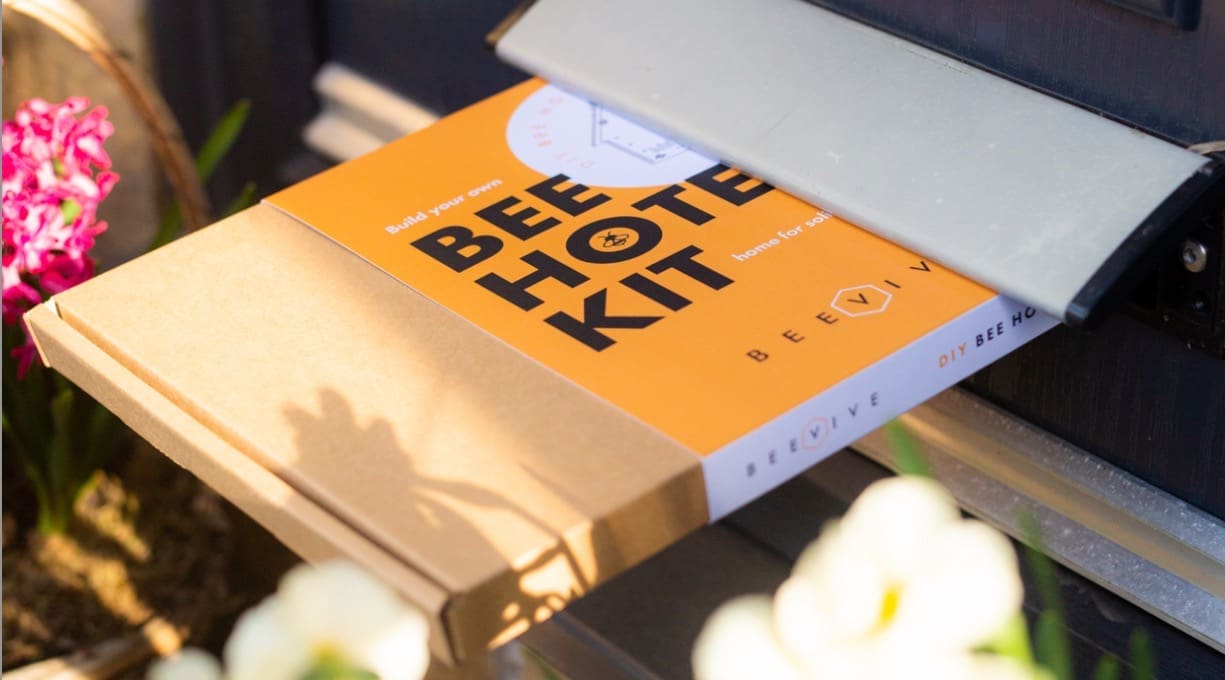 A bee hotel DIY kit being posted through a door