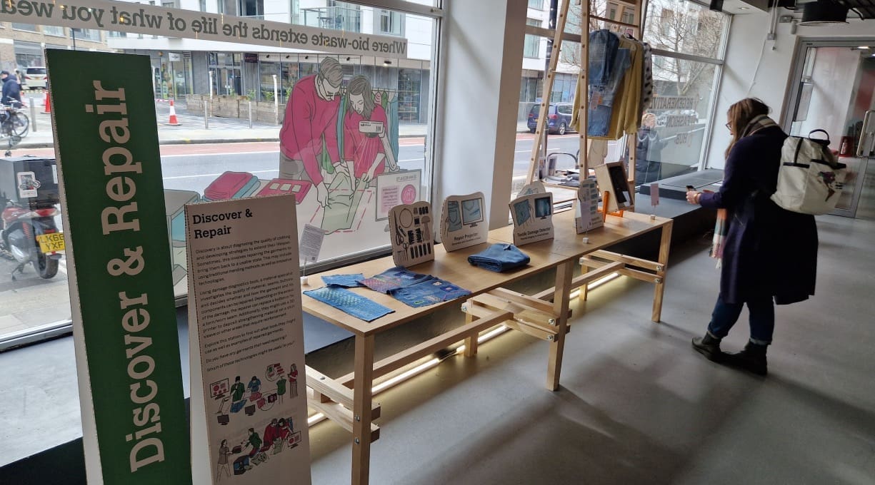 A table display of items of clothing and examples of how we might identify and repair damaged items in the near future.