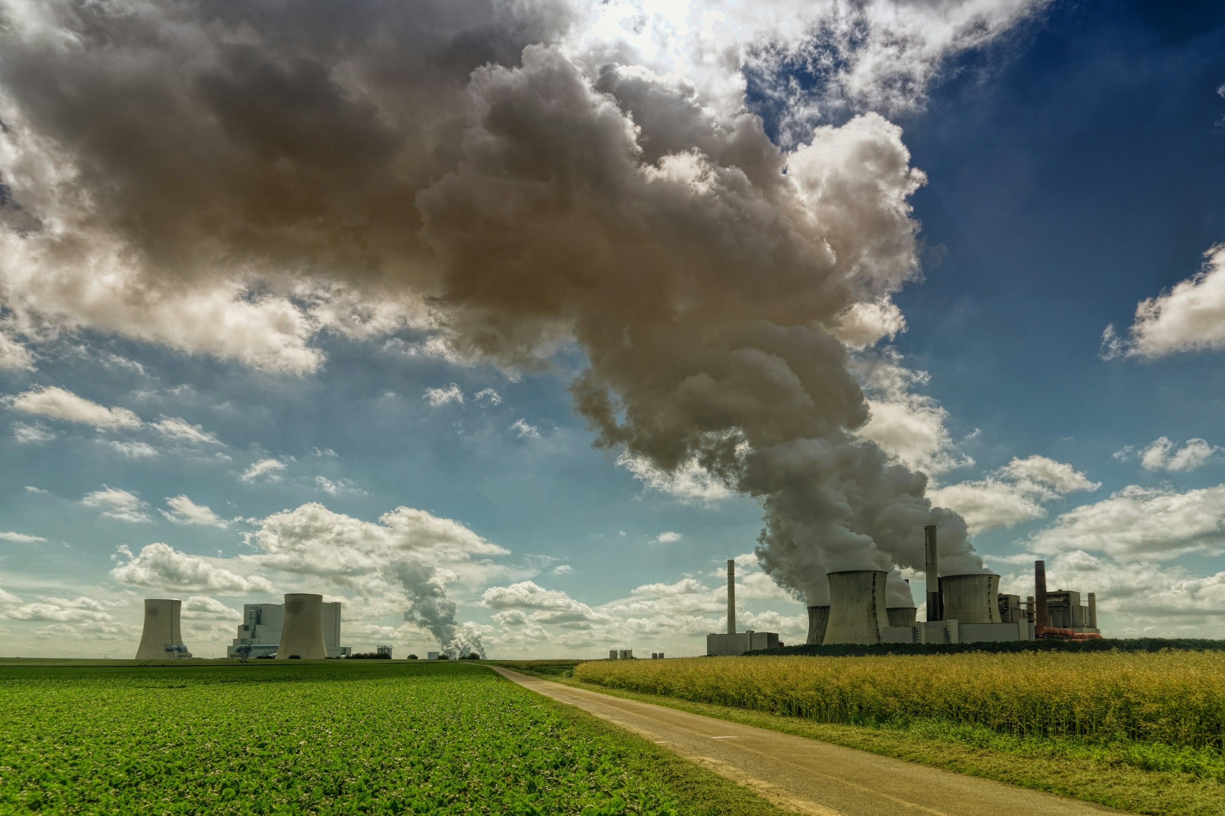 landscape with a factory billowing smoke into the air.