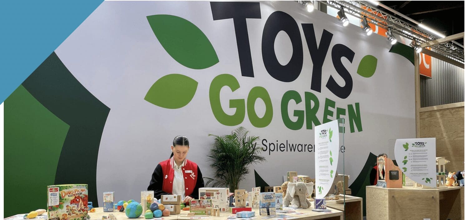Woman stands at a table filled with wooden and sustainable toys as she examines their sustainability credentials.