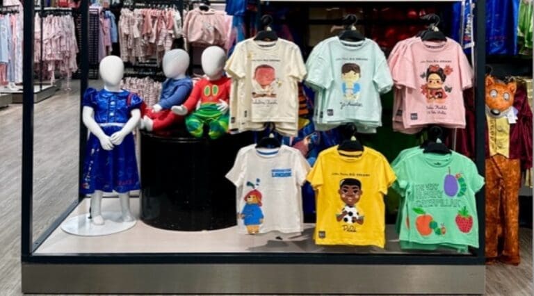 A collection of apparel feature Little People, BIG DREAMS graphics adorn a display wall in Tesco