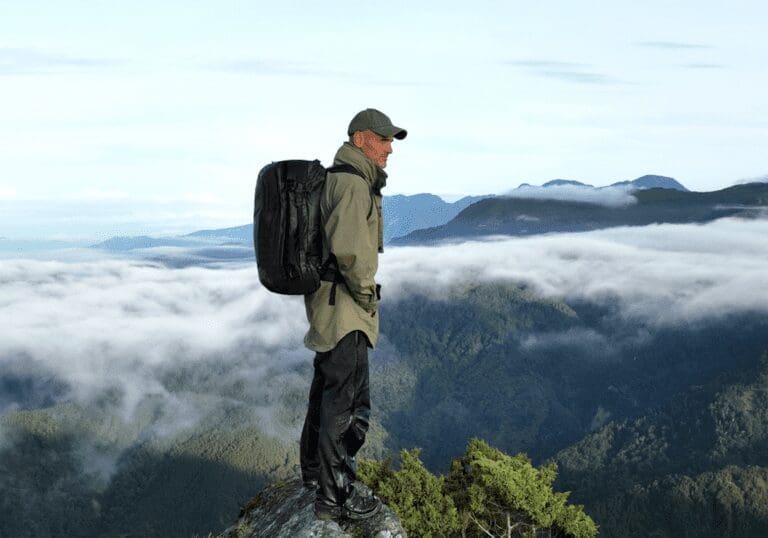 Ed Stafford stands atop a mounting wearing the Hybrid Duffle Pack and looking over the vista.