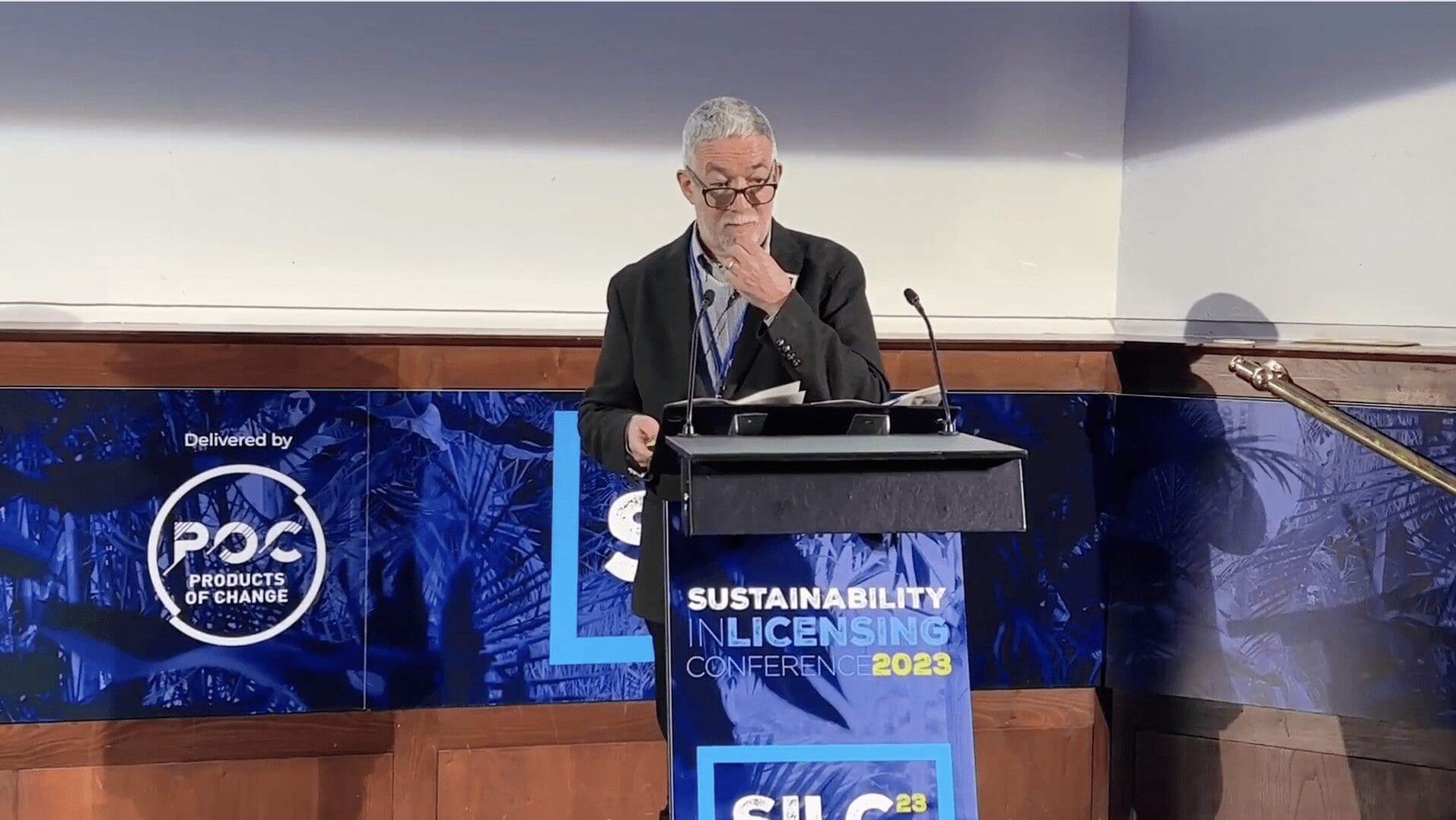 Man stands at lecture featuring Sustainability in Licensing Conference branding.