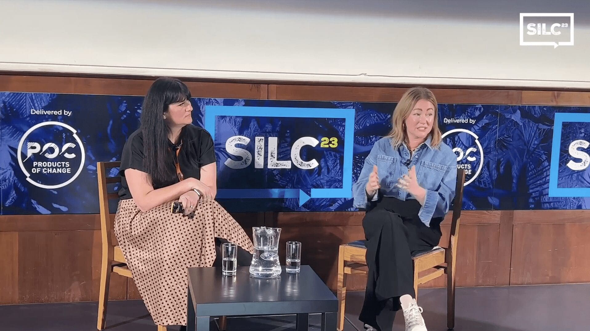 two women sat on chairs on stage in front of sustainability in licensing conference 2023 branding.