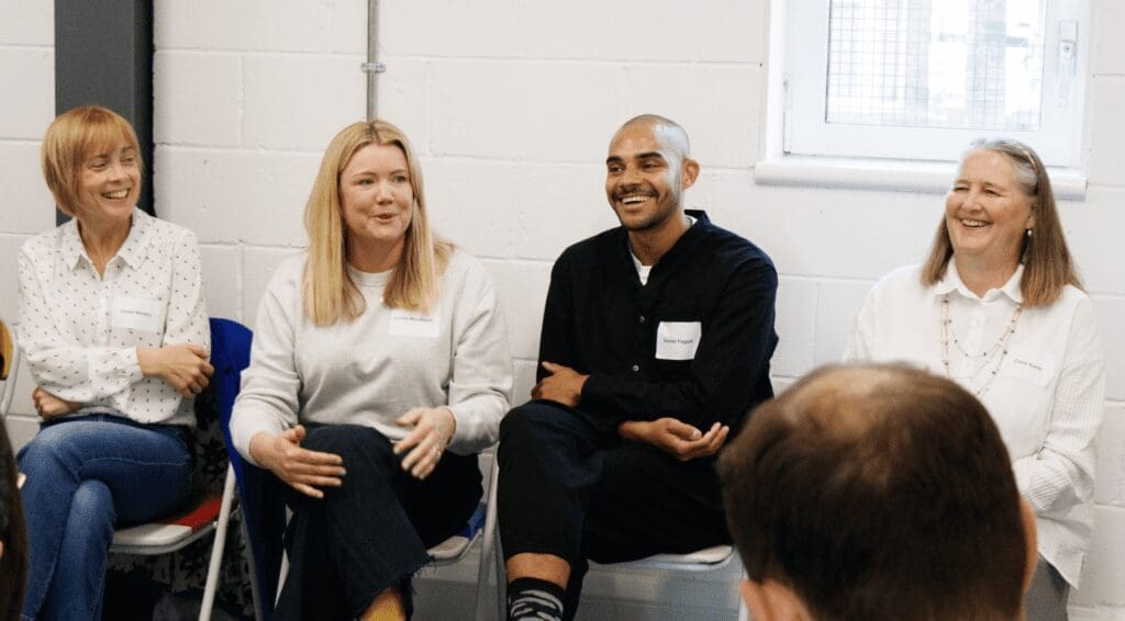 Four people sat smiling in a row hosting an informal panel discussion