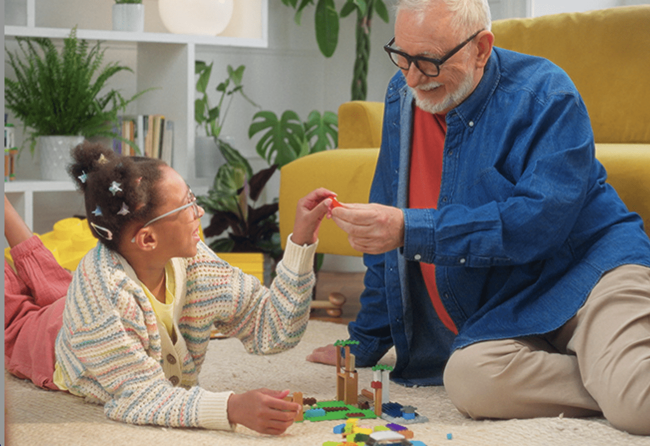 Young girl plays with lego bricks with her grandfather.