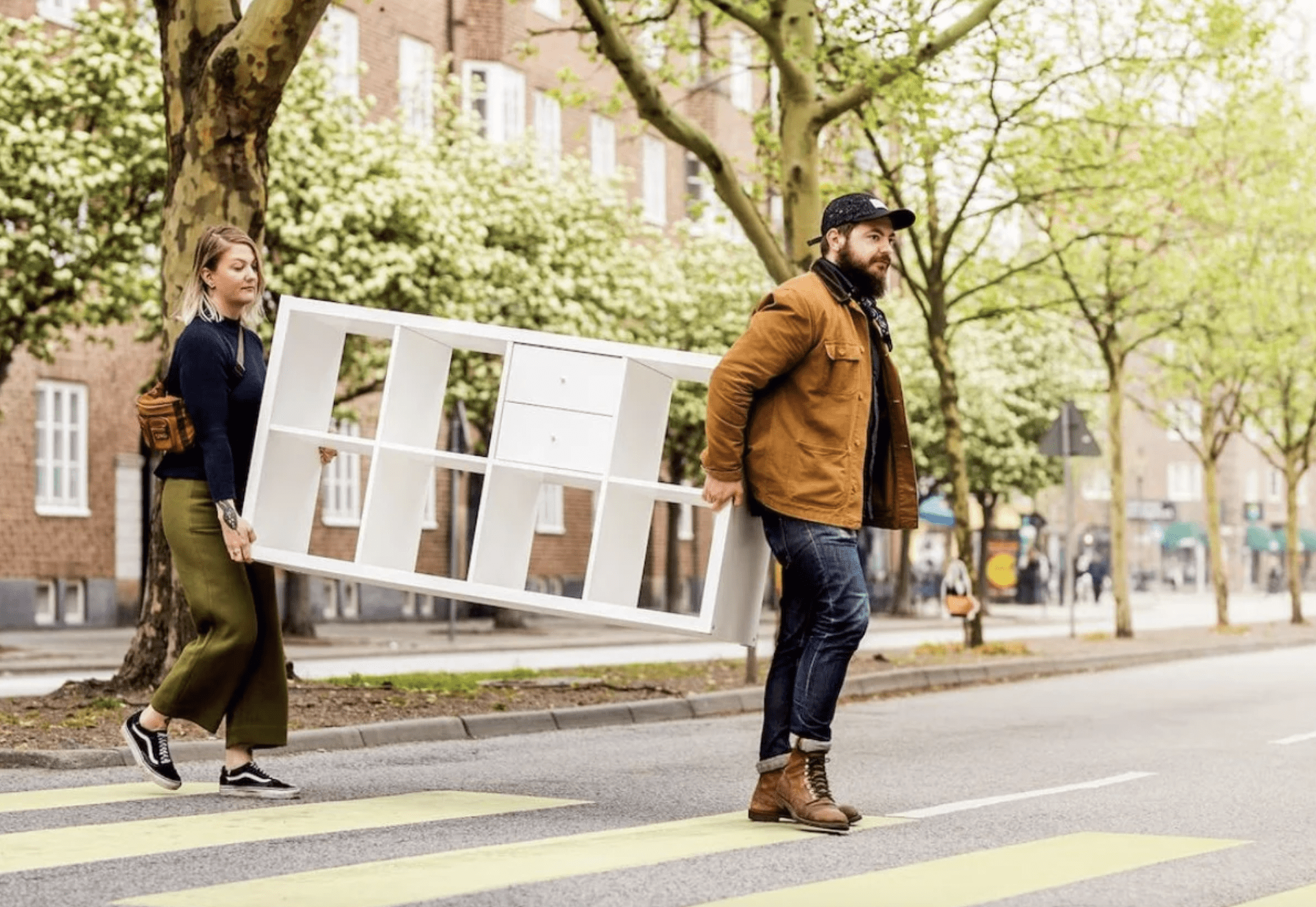 man and woman carry a cabinet across a road