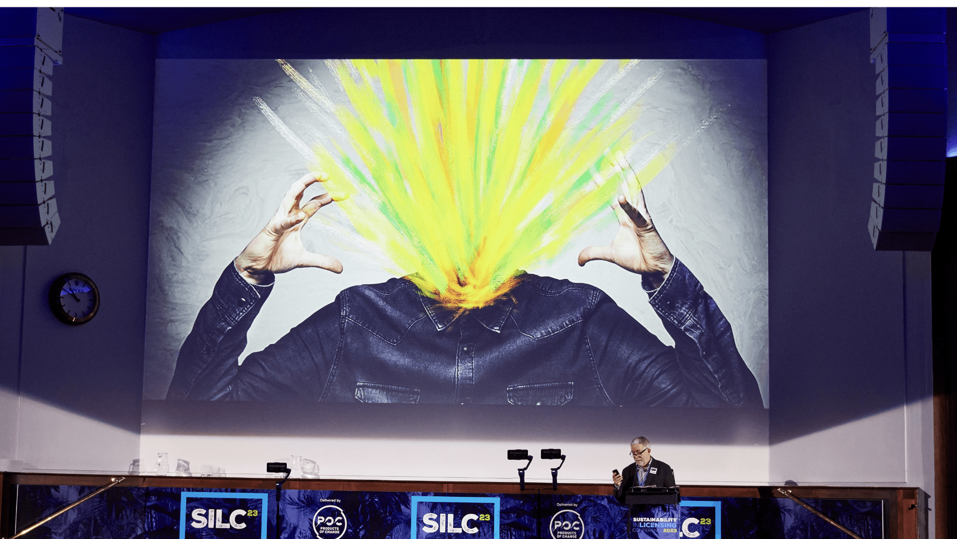 Illustration of a person's head colourfully exploding on presentation screen, with man in foreground presenting.