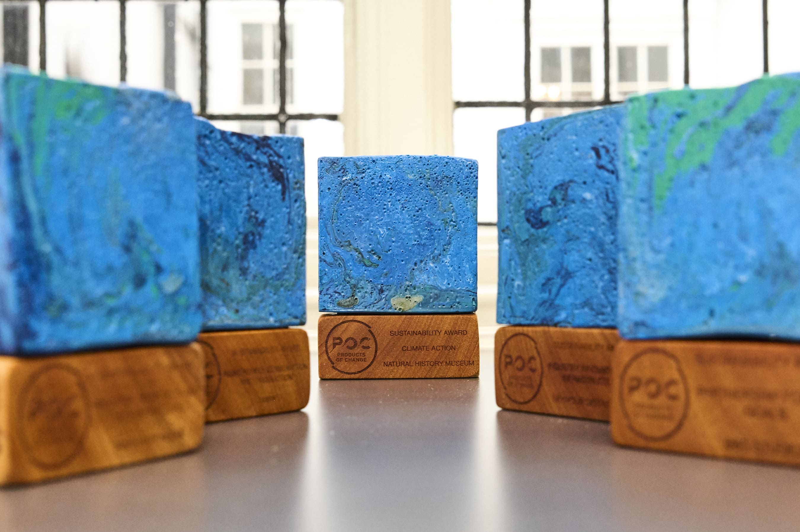 Six trophies comprised of blocks of marbled blue plastic on wooden plinths.