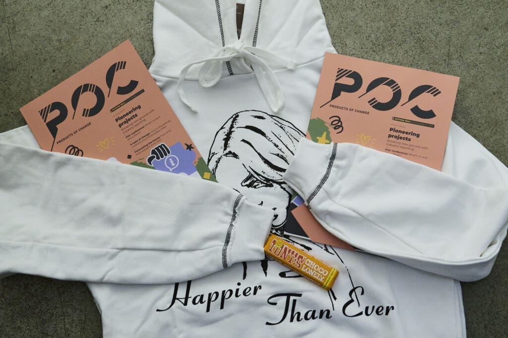A white hoodie with black print and two magazines and a chocolate bar