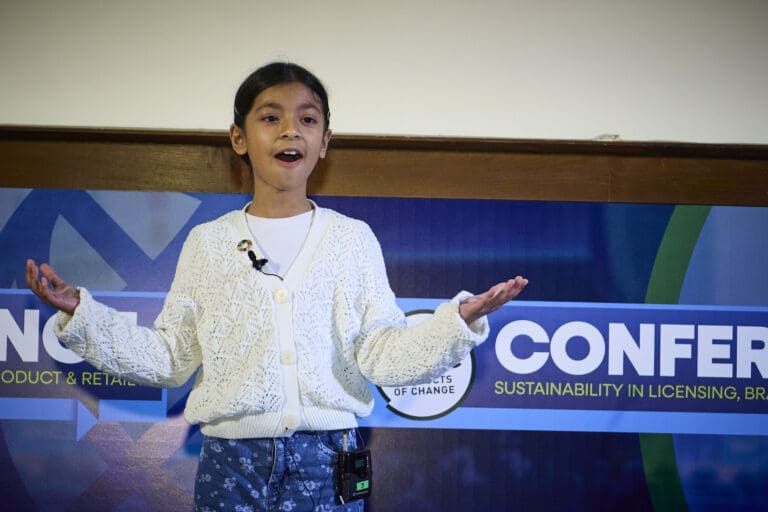 A young girl stands with her arms open addressing a audience