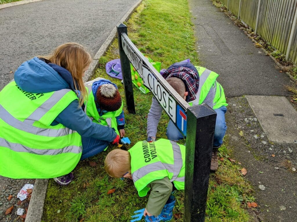 A woman and three children picking up rubbish from a residential street.