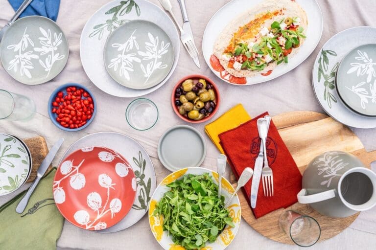 Overhead shot of a table laid with plates and napkins and mediterranean food.
