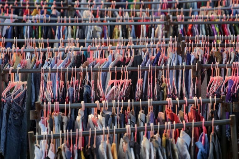 Numerous rails of clothes on hangers filling entire image.