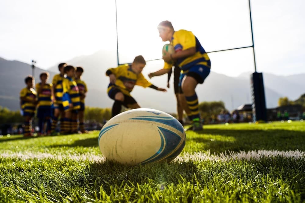 Rugby ball on pitch with players and goal posts