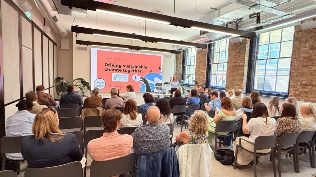 A group of people sitting in a room facing a screen with Helena presenting.