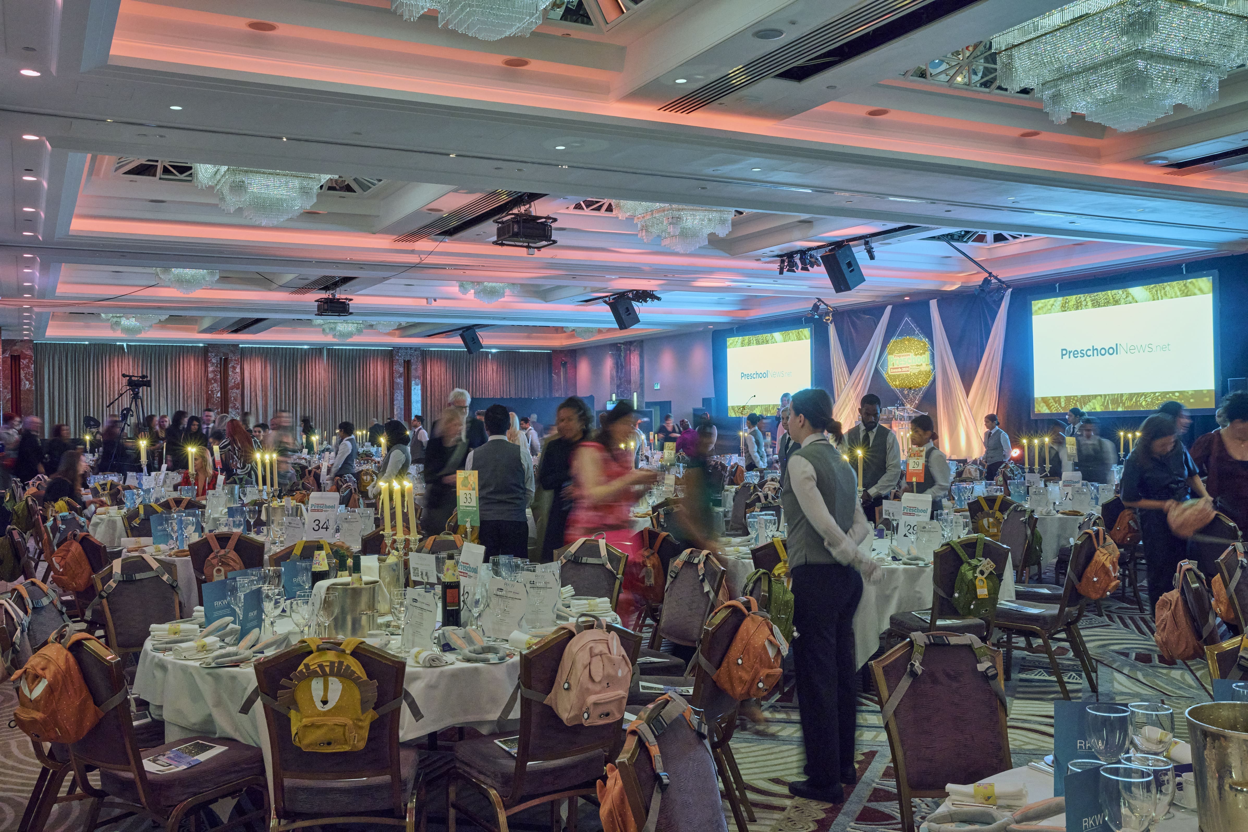 Ballroom full of tables as people gradually enter the room.